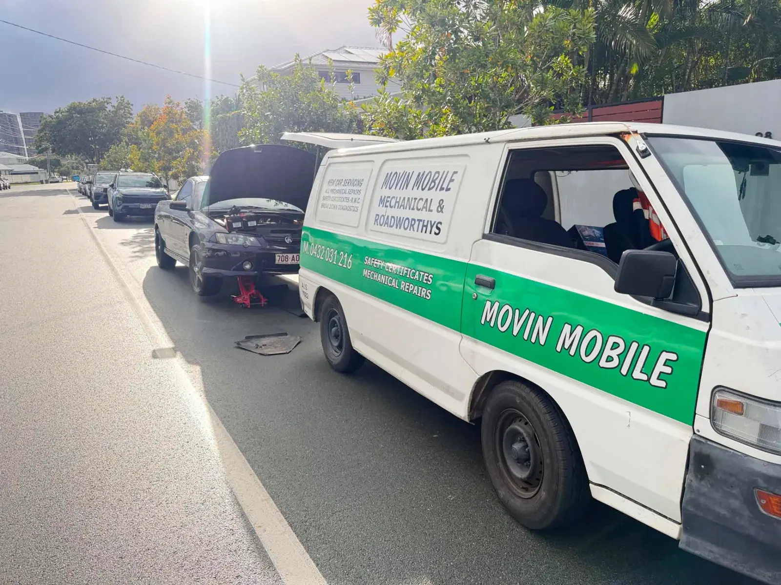 Movin Mobile Mechanic van and a Holden ute jacked up on a Gold Coast street with the bonnet open for on-site auto electrical repair