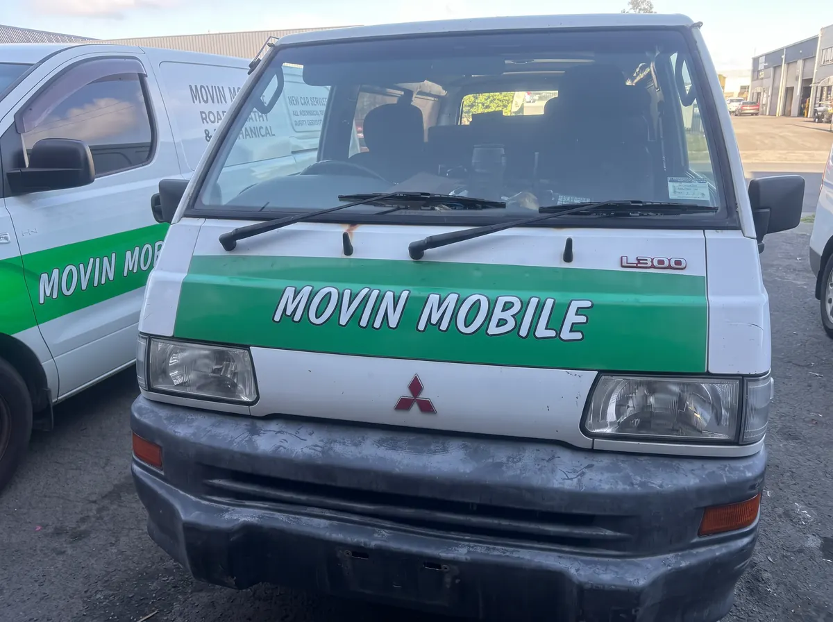 Front view of a white Movin Mobile Mitsubishi service van