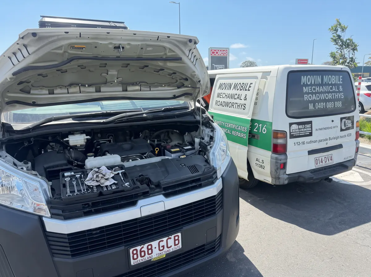 Open vehicle engine bay beside a Movin Mobile van