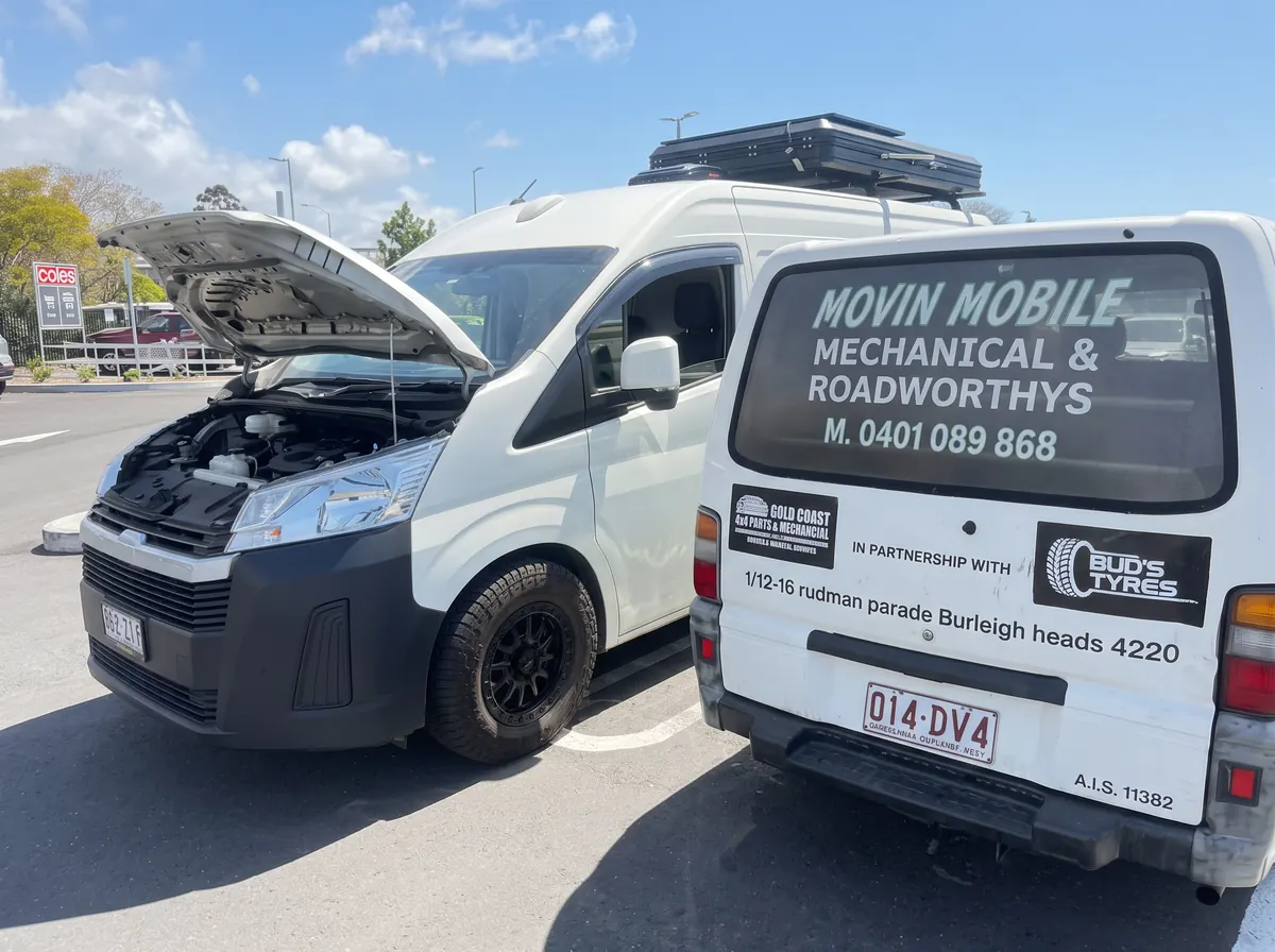 Two Movin Mobile vans parked next to a vehicle with its bonnet open