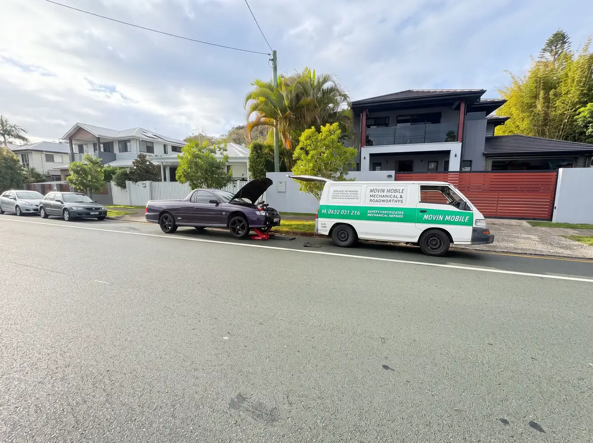 Movin Mobile van near a car with an open bonnet on a suburban street