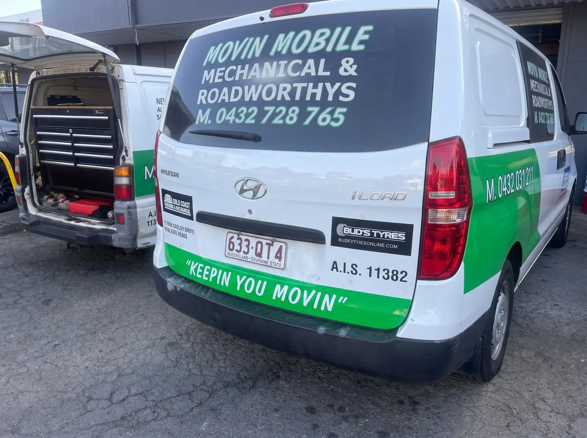 Rear of two Movin Mobile vans parked outside a workshop